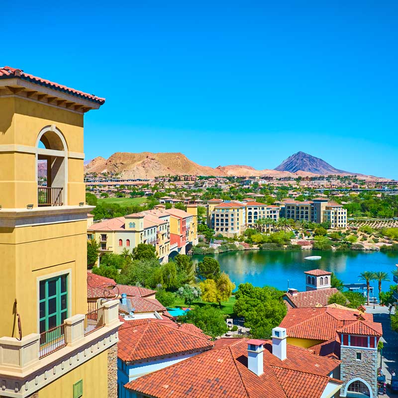 Mediterranean‑style lakeside village in Clark County with desert hills – comparing Nevada county closing speeds